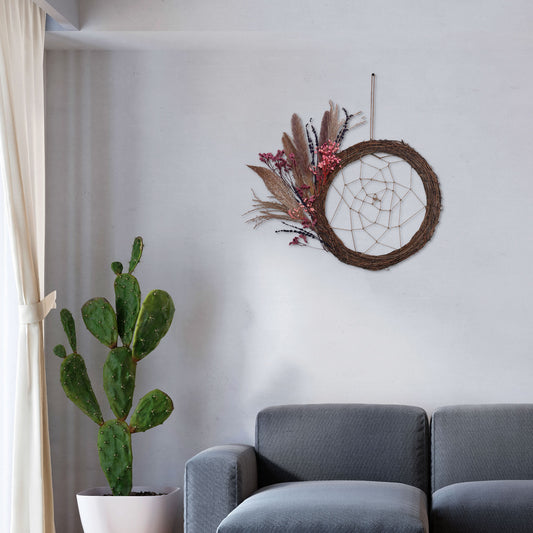 Bohemian dreamcatcher with circular grapevine wreath, jute thread web, and a spray of dried florals and pampas grass on one side.
