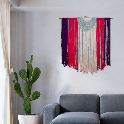 Medium handmade macramé wall hanging with vertical strands of purple, coral, ivory, and blush yarn, with a draped green semi-circle accent on top